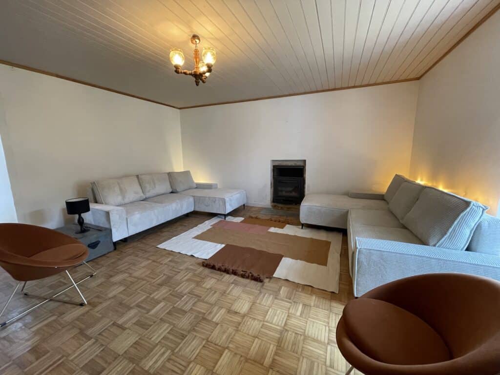 salon de la maison de vacances et de séminaire, La Maison Rosporden. Il est équipée de 2 grands canapés d'angle, de deux fauteuils confortables et d'un poêle à bois.