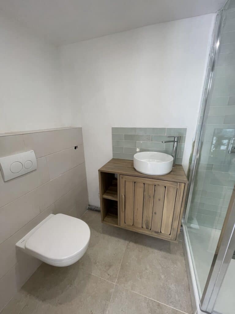 salle de bain de La Maison de vacances et de séminaire avec WC, meuble vasque et lave main, douche avec pluie.