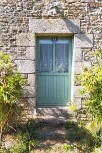 La porte d'entrée de La Maison Rosporden. Peinte en couleur vert d'eau et entourée de sa façade en pierres.